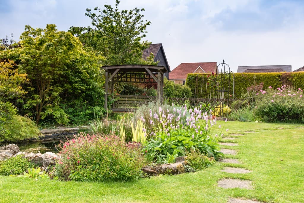 Jardin entretenu avec tonnelle en bois, bassin et massifs fleuris